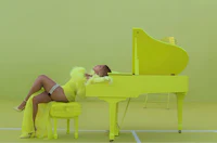 a woman in a yellow dress laying on top of a piano
