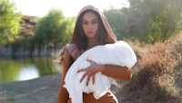 a woman wearing a hooded robe holding a baby