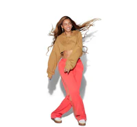 a woman in a tan cropped top and pink pants