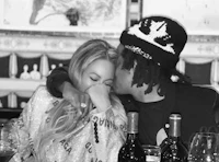 a black and white photo of a couple kissing at a table